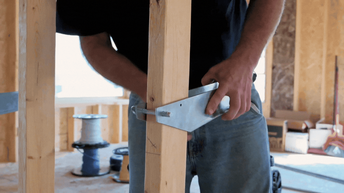 Person fastening metal bracket to wooden stud