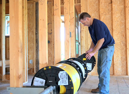 Man working with electrical wire spools in a wooden framed room