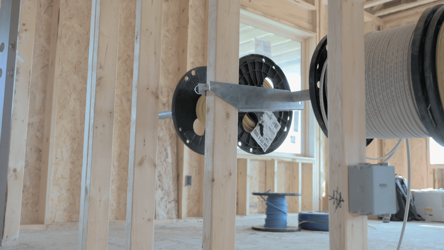Spools of cable on dispensing system mounted on wooden stud in a wooden framed building