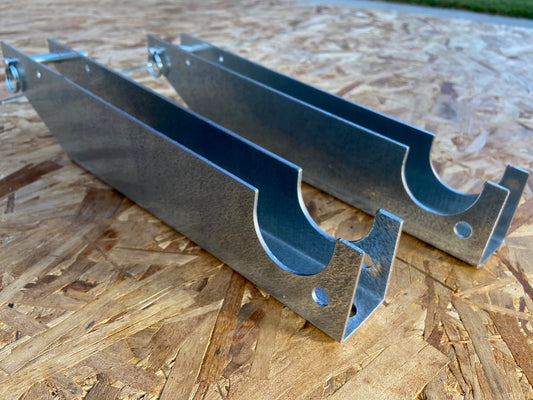 Two silver metal brackets placed on a wooden surface.