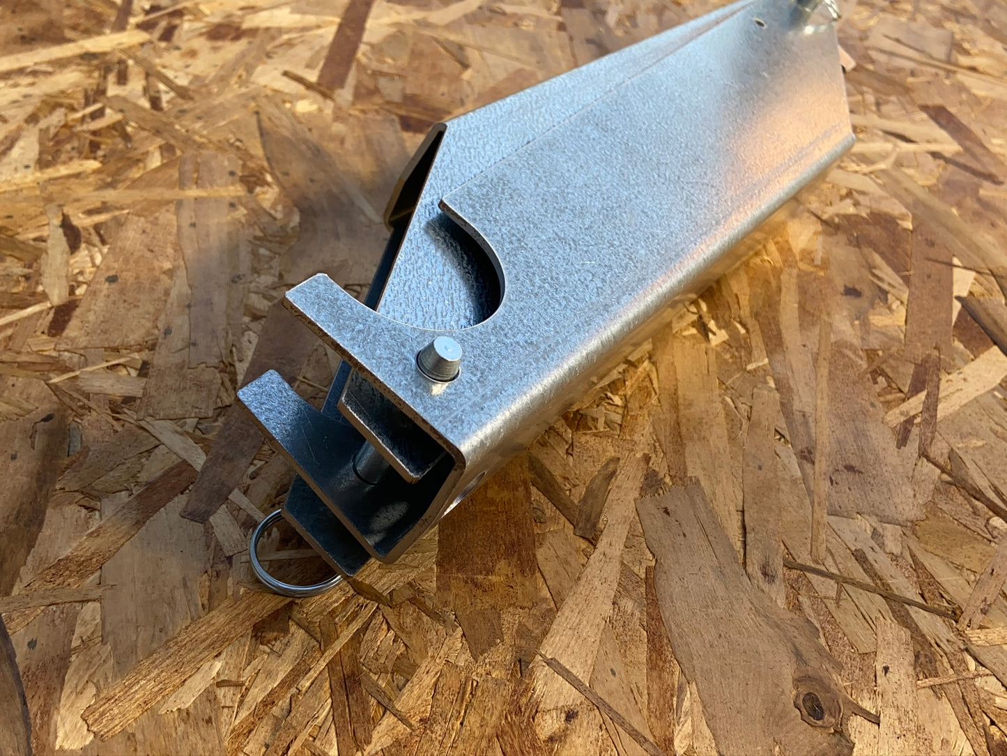 Two steel brackets interlocked and connected with detent pins and laying on plywood. 
